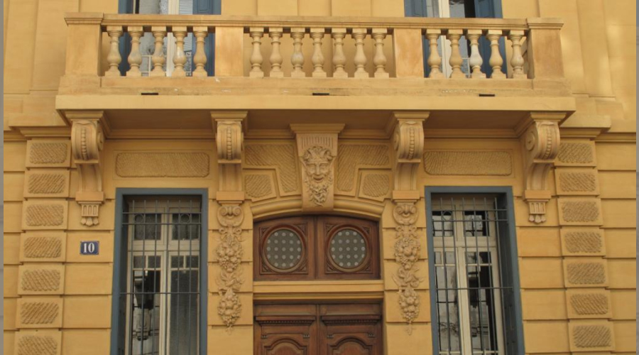 Façade peinte en ocre jaune ,balcon à balustres au 1er,guirlandes et tête de faune ornant les piedroits et linteau de l'entrée