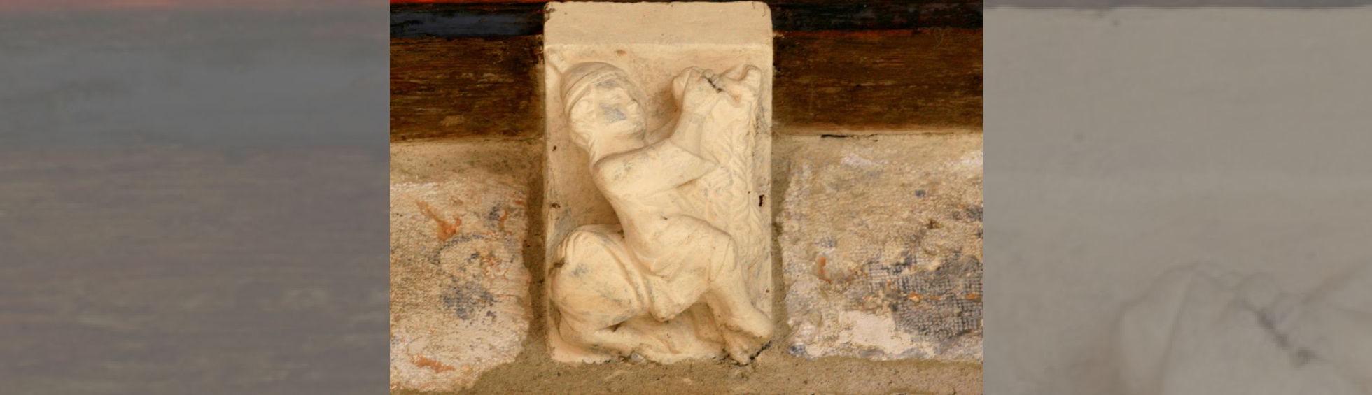 Sculpture d'un cavalier sur un chameau servant de support à une poutre dans le passage d'entrée