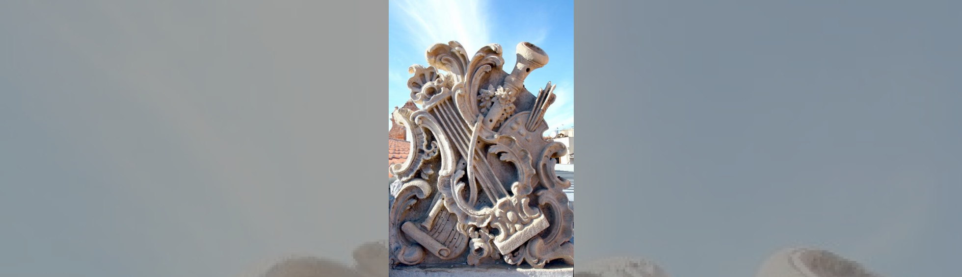 La sculpture repésente une lyre , une flute ,une partition, une palette de couleurs avec ses pinceaux