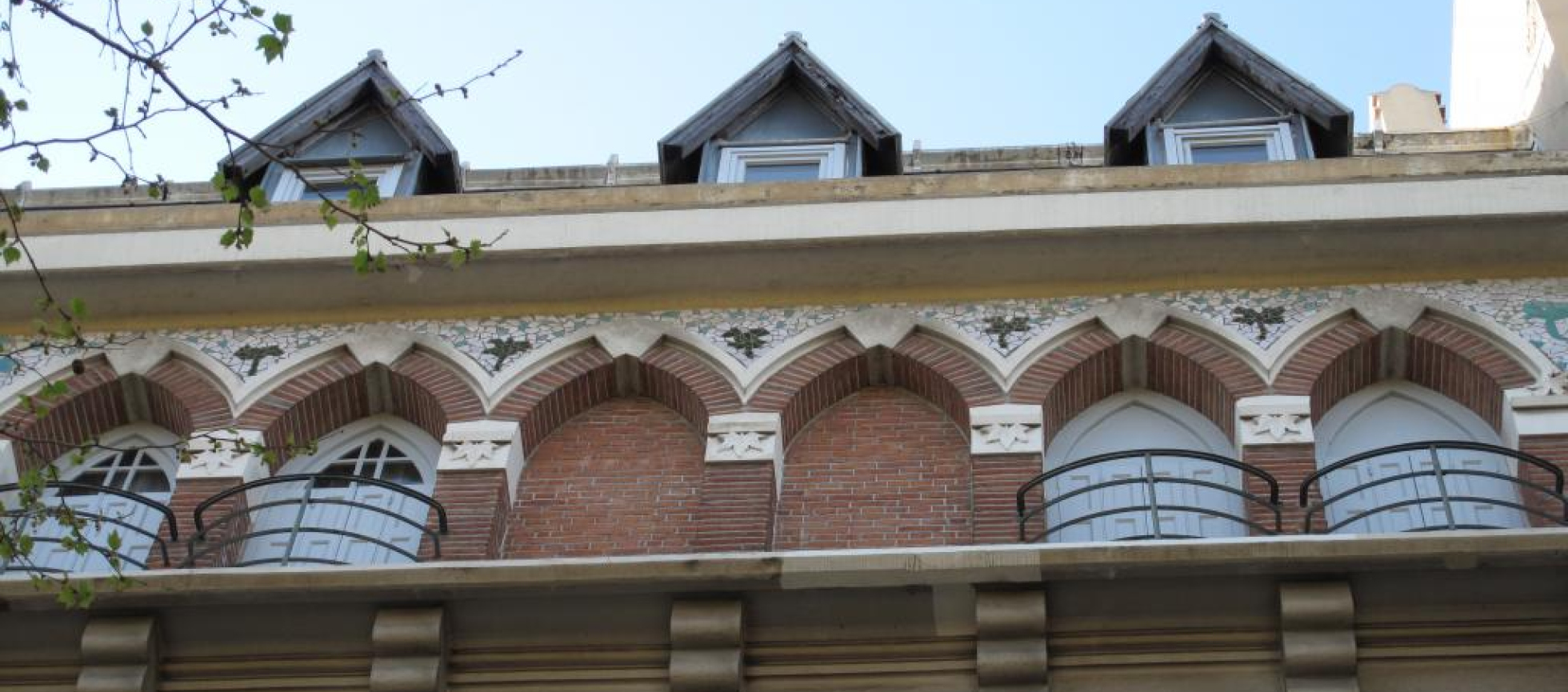 Succession d'arcs brisés supportant une corniche puis des chiens assis triangulaires.