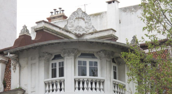  Angle du dernier niveau traité en courbe : 3 fenetres , balcons a balustres, sur le toit une couronne de branches de pin 